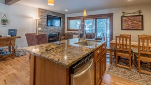 A modern kitchen with granite countertops, a built-in dishwasher, and wooden chairs.