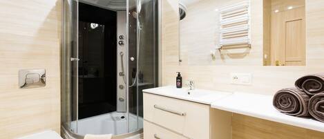 A modern bathroom with a glass-enclosed shower, a white toilet, a vanity with a mirror, and a towel rack.