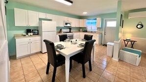 A compact kitchen with white cabinets, a dining table set for four, and a central island.