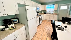 A compact kitchen with white cabinets, a refrigerator, stove, and a dining area with a table and chairs.