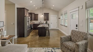 A spacious kitchen with dark wood cabinets, a central island, and a dining area with a patterned chair.