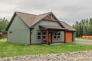 En tvåvåningsbyggnad med ett sadeltak, ett garage som vetter mot framsidan och en liten veranda.