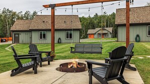 An outdoor seating area with Adirondack chairs and a fire pit.