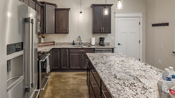 A modern kitchen with dark wood cabinets, stainless steel appliances, and a granite countertop.