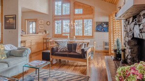Ein gemütliches Wohnzimmer mit Kamin, Holzmöbeln und großen Fenstern.