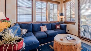 Un salon avec un canapé bleu, une table basse ronde et une plante en pot.