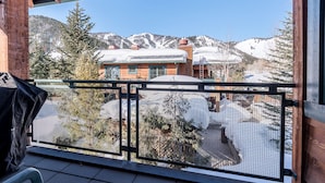 Un balcon offrant une vue sur une maison de montagne et un paysage enneigé.