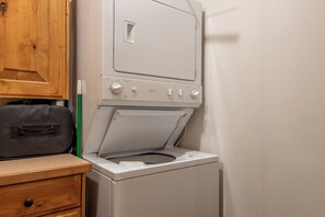 Una lavadora y secadora compactas con un gabinete de madera y una bolsa negra sobre la encimera.
