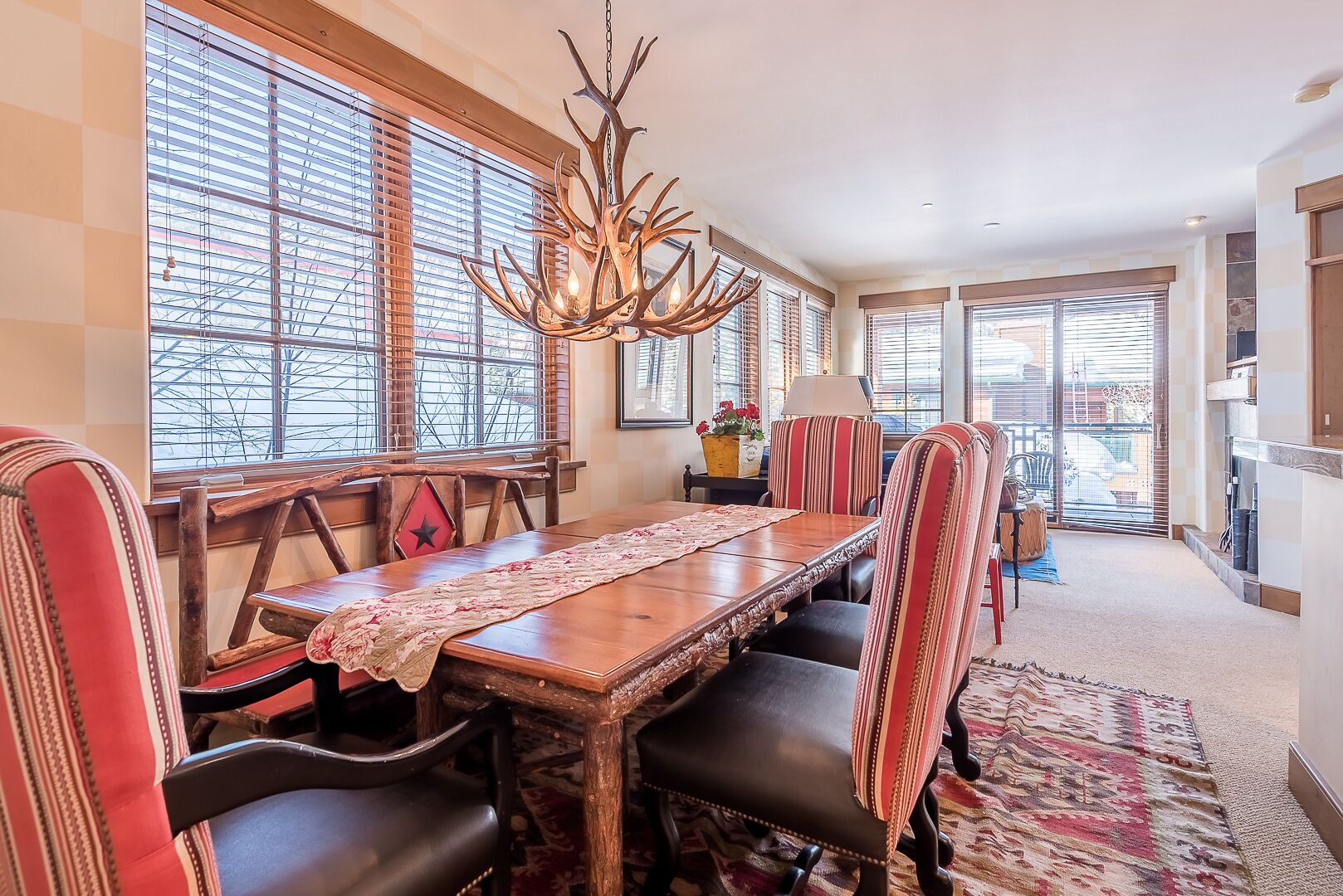 A dining area with a wooden table, striped chairs, and a chandelier.