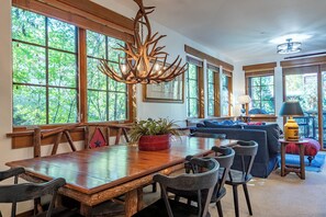 A dining area with a wooden table, chairs, and a chandelier with antlers.