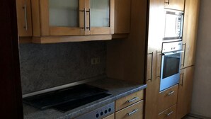 Uma cozinha com armários de madeira, fogão embutido e micro-ondas.