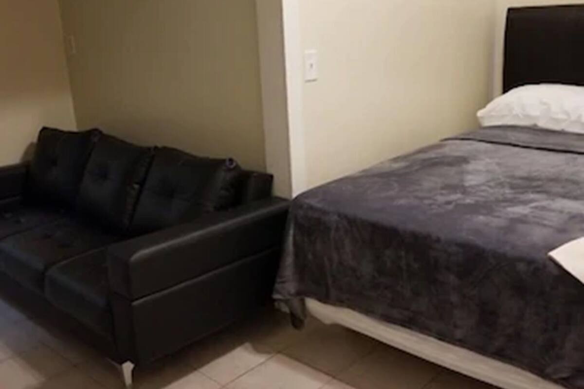 Ein kleiner, schlichter Raum mit einem Bett, einem Schlafsofa und einem Bild an der Wand.