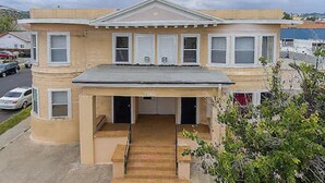 A two-story building with a covered front porch, a garage, and a driveway. - Pads on Pasadena Ave (Los Angeles)