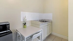 A compact kitchenette with a microwave, a small table, a chair, and a sink. - Pads on Pasadena Ave (Los Angeles)