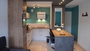 A compact kitchen with white cabinets, a built-in oven, and a small dining area with a table and chairs.