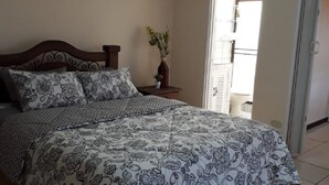 A bedroom with a large bed, a nightstand, a potted plant, and a painting on the wall. - Private Apartment House 2 Bedroom 5 mins SJO Airport Furnished Spacious Kitchen (Alajuela)