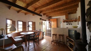 Une cuisine rustique avec des poutres en bois, un coin repas avec une table et des chaises, et un mur en pierre.