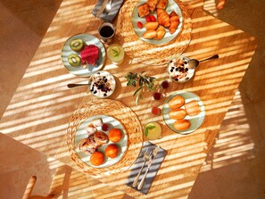 A table set with various dishes, including fruits, pastries, and a bowl of yogurt with granola. - Amantes Villas and Suites (Sithonia)
