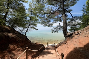 A wooden staircase leading down to a beach, surrounded by trees and rocky terrain. - Amantes Villas and Suites (Sithonia)