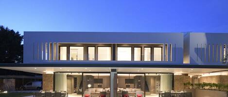 A modern two-story house with a swimming pool in the front.