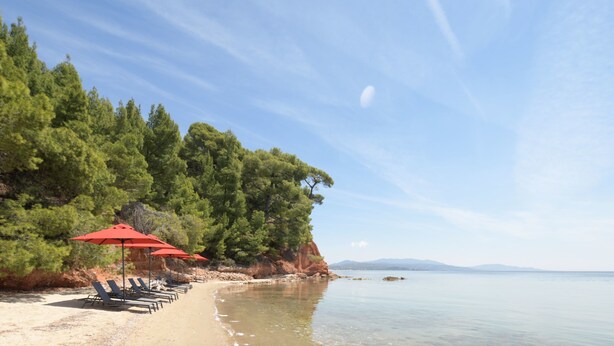 Privat strand, sort sand, solsenger og parasoller