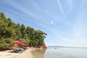 Playa privada, arena negra, sillas reclinables de playa, sombrillas