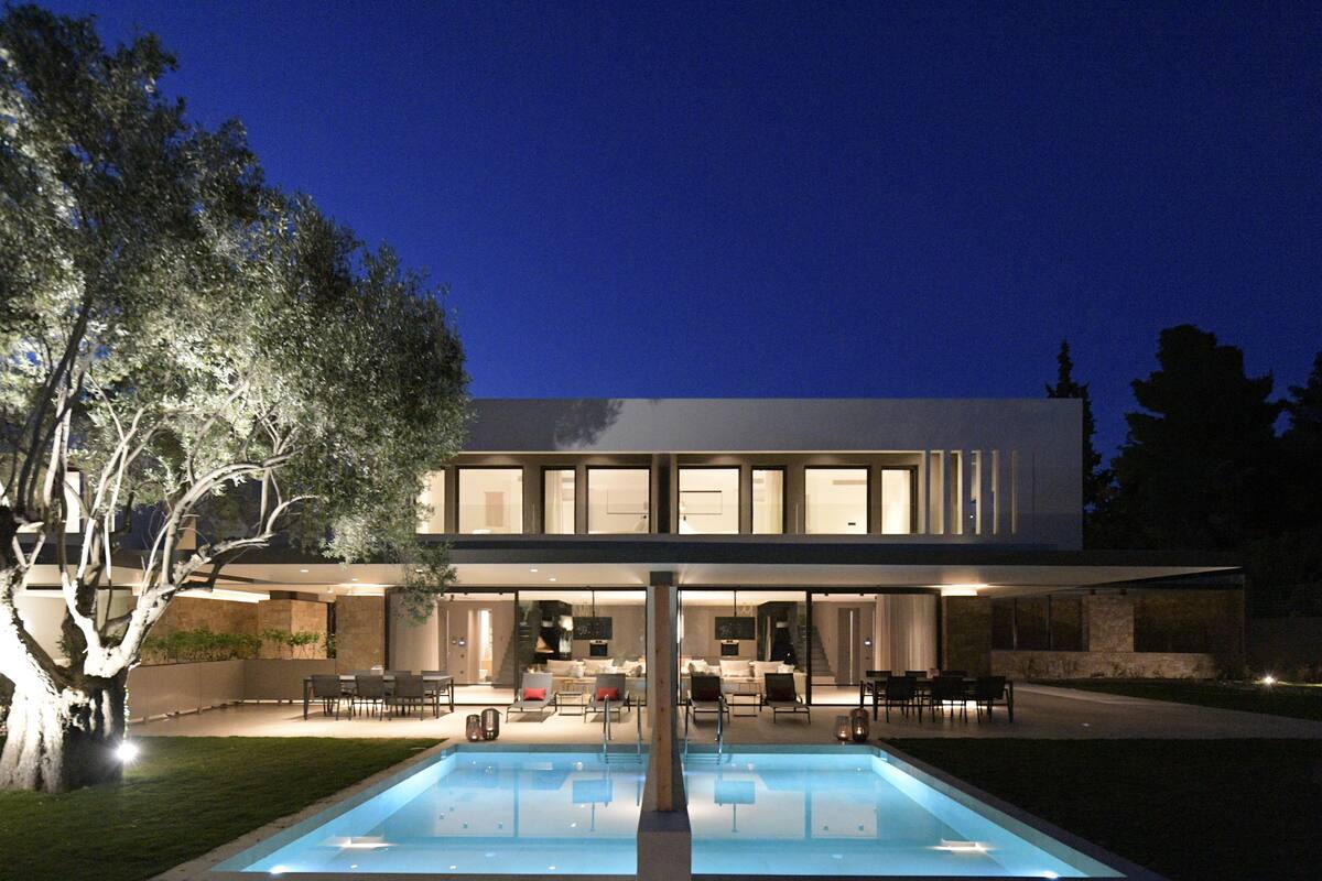 Una casa moderna de dos pisos con una piscina delantera.