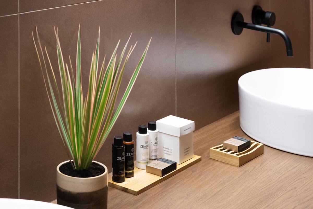 Un baño con una planta en maceta, un lavabo y artículos de aseo sobre una bandeja de madera.