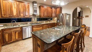 A spacious kitchen with wooden cabinets, stainless steel appliances, and a large island with bar stools. - 6 BR Enormous, 4700 Square Foot Vacation Home in a Scenic Mountain Setting! (Boone)