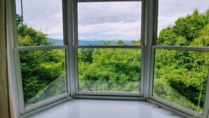 A corner room with a large window offering a view of lush greenery and distant hills. - 6 BR Enormous, 4700 Square Foot Vacation Home in a Scenic Mountain Setting! (Boone)