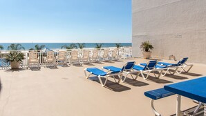 Balcón frente al mar con sillones de descanso y una mesa.