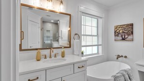 Een bad/douchecombinatie, een bubbelbad, een haardroger, handdoeken