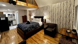 Una camera da letto con un letto, una scrivania, una sedia, un tavolino e un soffitto in legno.