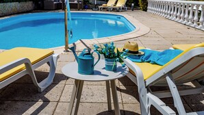 Ein Poolbereich mit Tisch, Stühlen, einem Gießkann und einem Blumenstrauß.