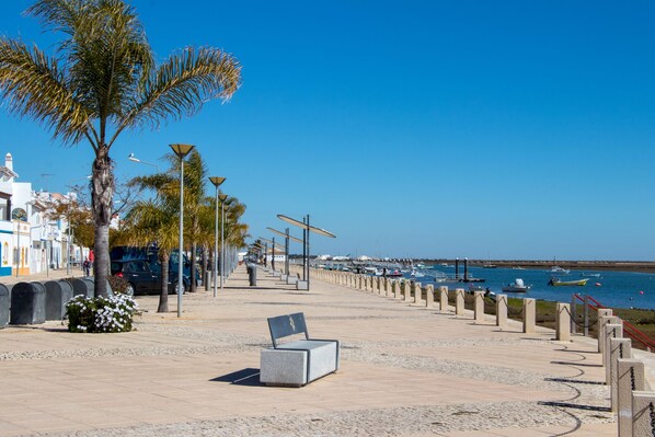 A coastal promenade with a bench, palm trees, and a marina in the background. - Lovely 3 bed 2 bath bungalow, private pool, 5 mins from Praia Verde 94153/AL (Castro Marim)