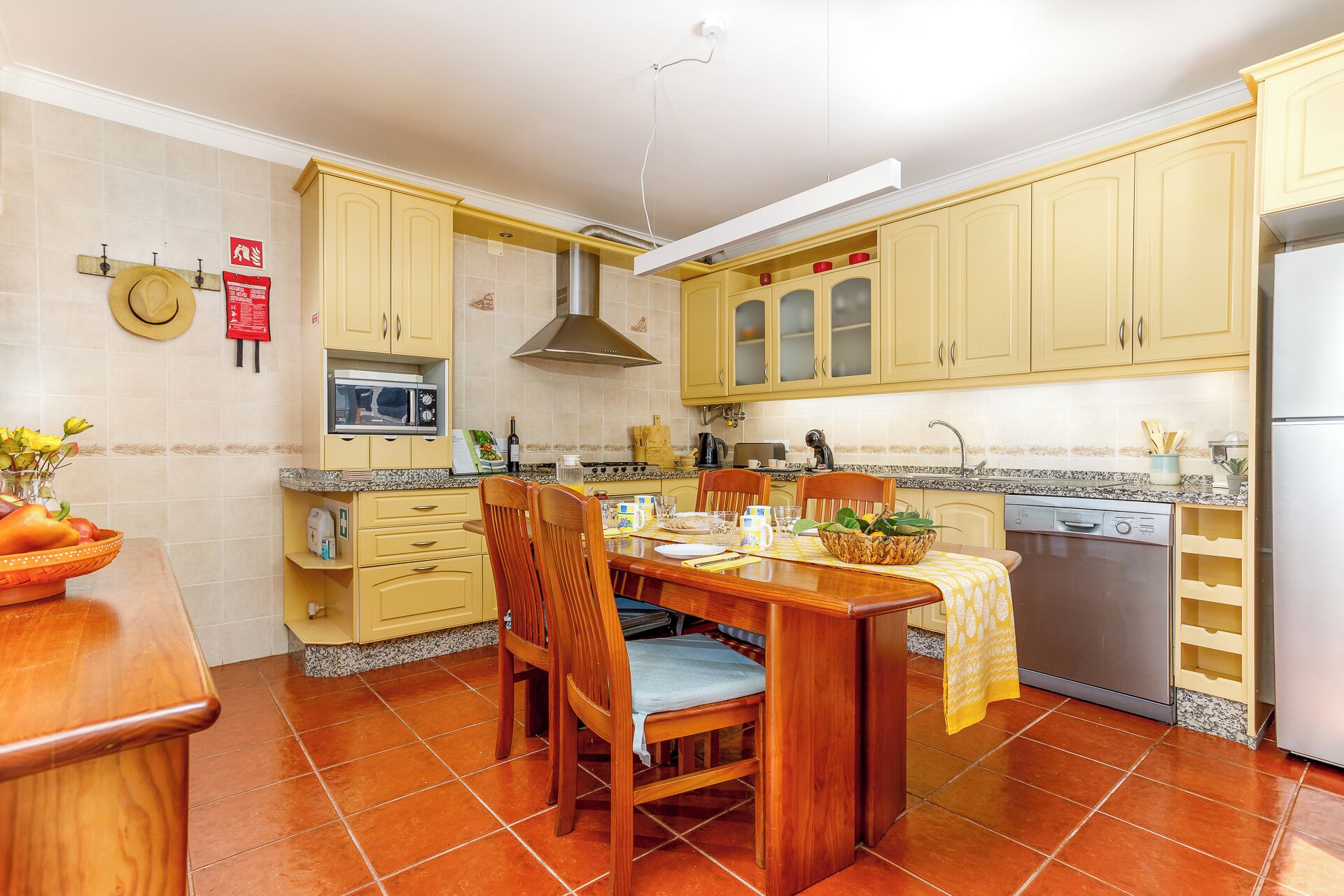 A kitchen with yellow cabinets, a dining table with chairs, a microwave, a stove, and a dishwasher.