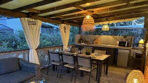 An outdoor deck with a dining area, kitchen, and seating.