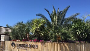 A sign for the Toussaint River Village with a bamboo fence and palm trees.