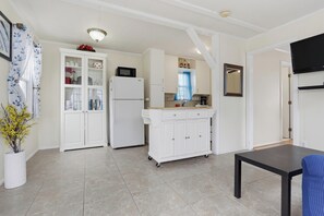 Cocina compacta con armarios blancos, un microondas y un lavamanos.