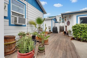 A wooden deck with potted plants and a barbecue grill.