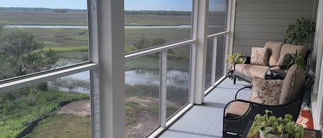 A covered outdoor seating area with a view of a water body and vegetation.