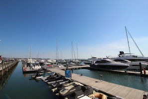Ein Yachthafen mit mehreren vertäuten Booten, einer Holzsteganlage und blauem, wolkenlosem Himmel.