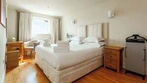A spacious bedroom with a large bed, bedside tables, a chair, and a wardrobe. - Crow's Nest - Directly on Poole Quay (Poole)