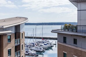 Un port de plaisance où sont amarrés des bateaux, entouré de bâtiments modernes dotés de grandes fenêtres et de balcons.