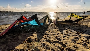 Ein Strand mit Drachen und ruhiger See.
