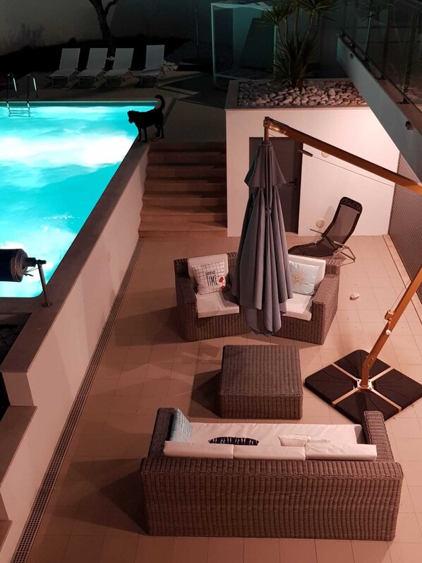 A poolside area with wicker furniture, a lounge chair, and a small table.