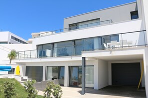 A modern two-story building with large windows, a balcony, and a garage. - Casa Sol & Mar, Stunning Oceanview pool (Lourinhã)