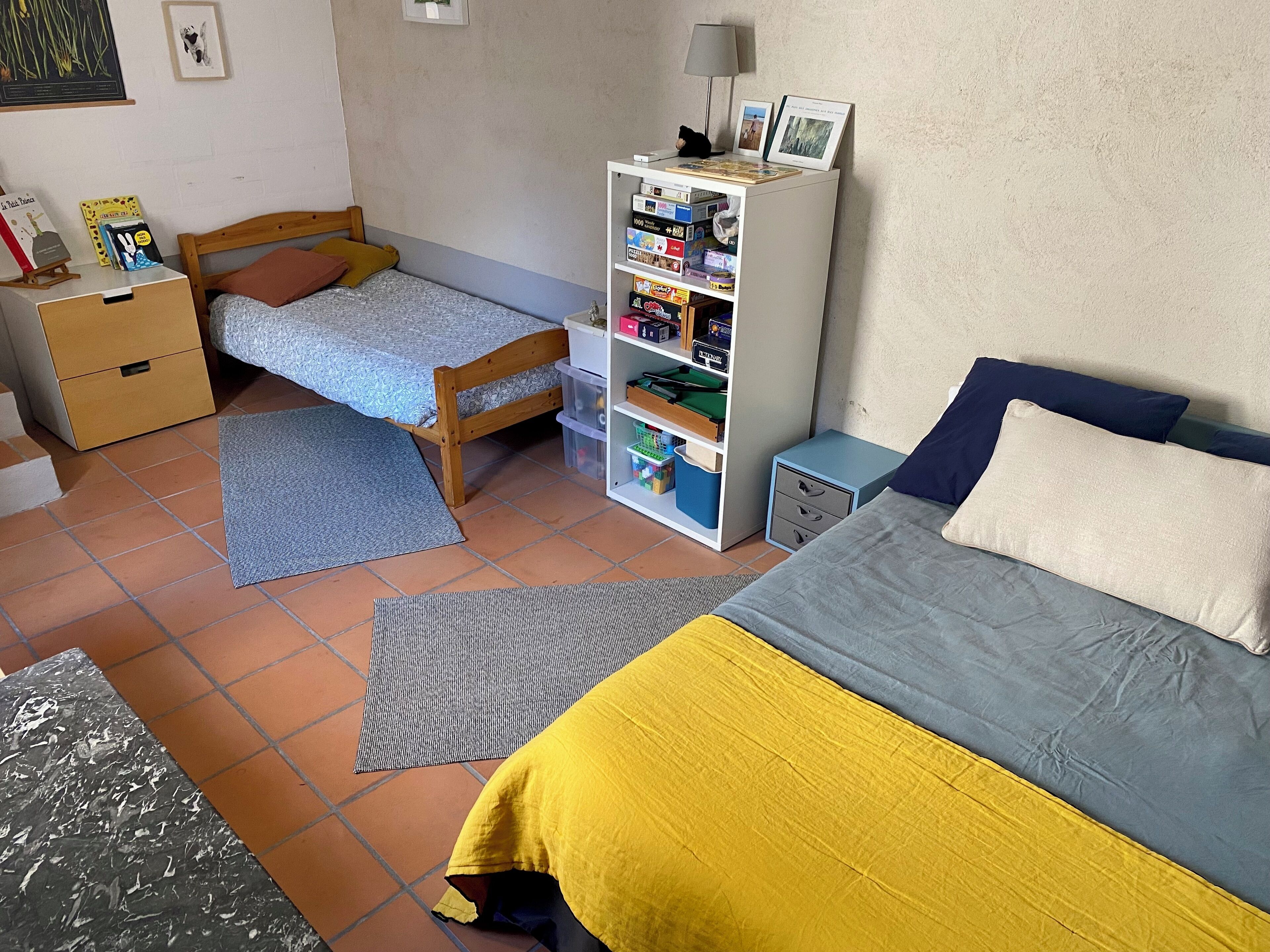 A bedroom with a bed, a nightstand, a bookshelf, and a desk.