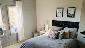 A bedroom with a bed, a nightstand, a window with curtains, and wall decorations.