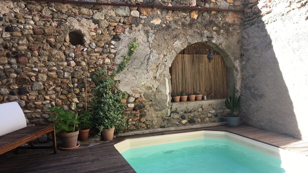 A stone wall with a wooden bench and a small pool.